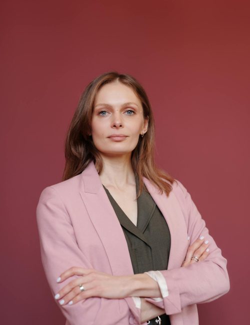Elegant businesswoman with arms crossed in studio portrait, showcasing leadership and confidence